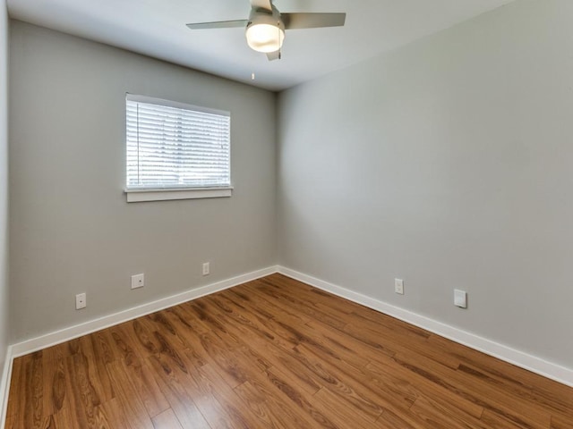 unfurnished room with a ceiling fan, wood finished floors, and baseboards