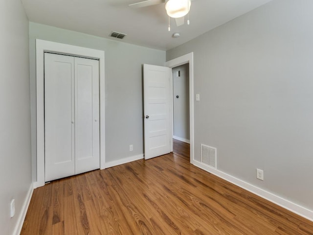 unfurnished bedroom with a closet, visible vents, baseboards, and wood finished floors