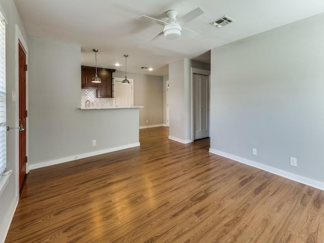 unfurnished living room with ceiling fan, visible vents, baseboards, and wood finished floors