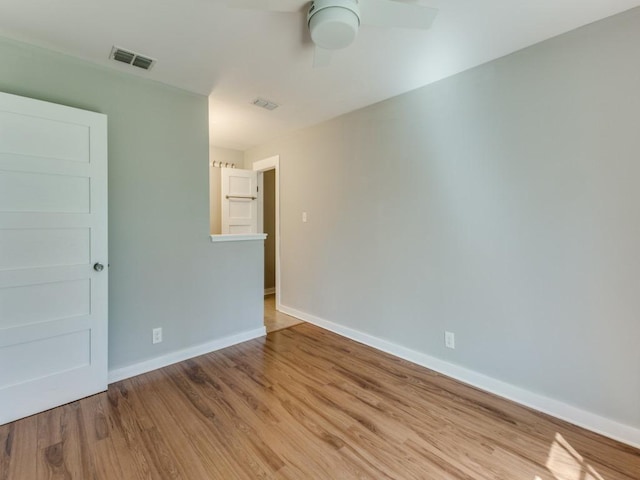 empty room featuring visible vents, a ceiling fan, baseboards, and wood finished floors