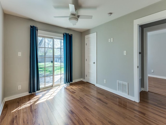 empty room featuring visible vents, baseboards, wood finished floors, and a ceiling fan