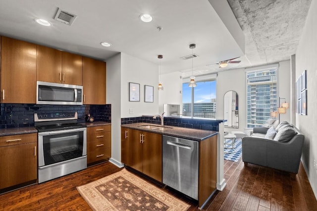 kitchen with open floor plan, a peninsula, stainless steel appliances, and visible vents