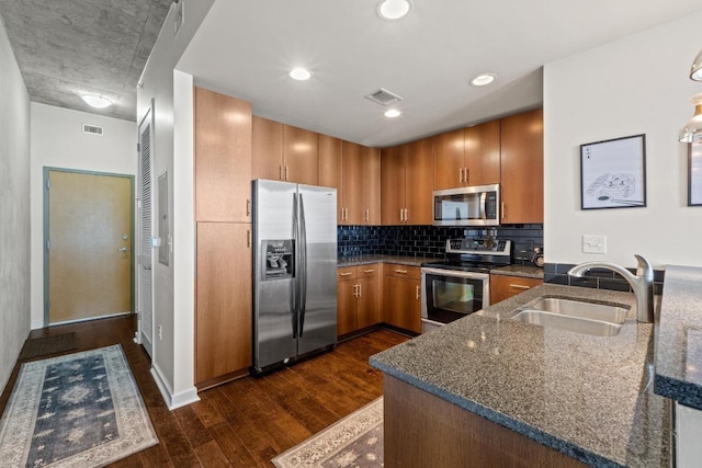 kitchen featuring visible vents, brown cabinets, a sink, dark wood finished floors, and stainless steel appliances