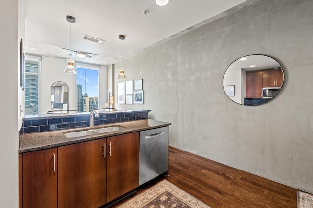 kitchen featuring visible vents, dark wood finished floors, dark stone counters, stainless steel appliances, and a sink