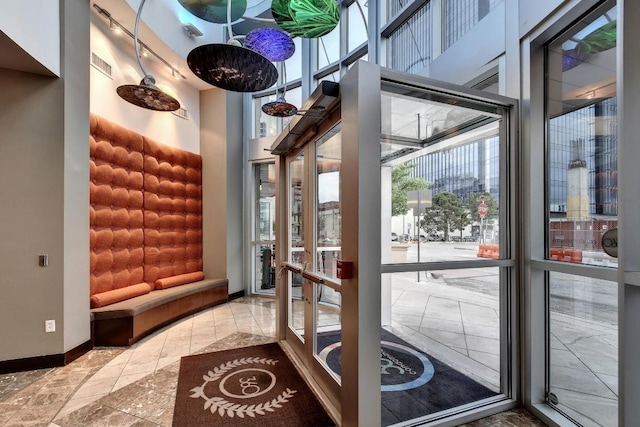 doorway to outside with visible vents, a healthy amount of sunlight, baseboards, and a towering ceiling