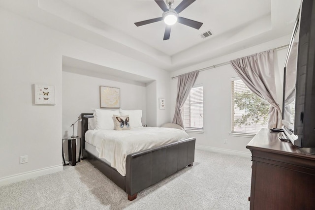 bedroom featuring a raised ceiling, baseboards, visible vents, and light carpet