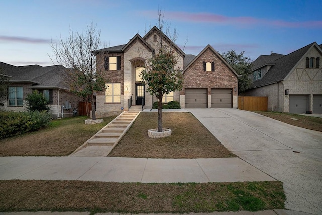 view of front of home with brick siding, an attached garage, fence, stone siding, and driveway