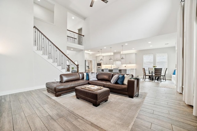 living area featuring stairs, recessed lighting, baseboards, and light wood-type flooring