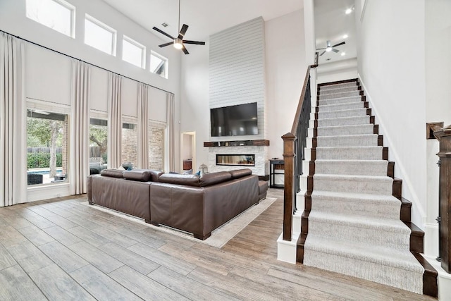 living area with plenty of natural light, a fireplace, ceiling fan, and wood finished floors