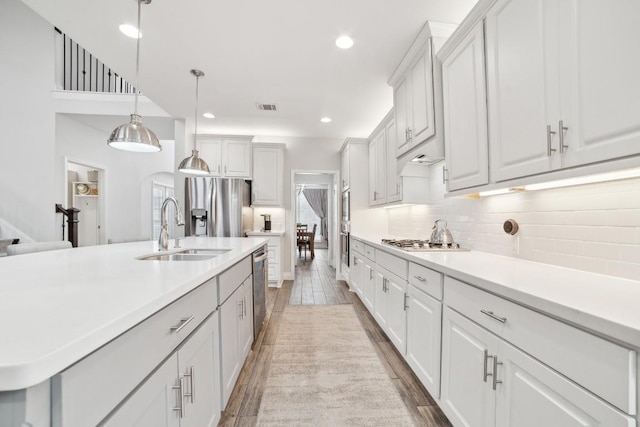 kitchen featuring visible vents, a sink, light wood-style floors, appliances with stainless steel finishes, and tasteful backsplash