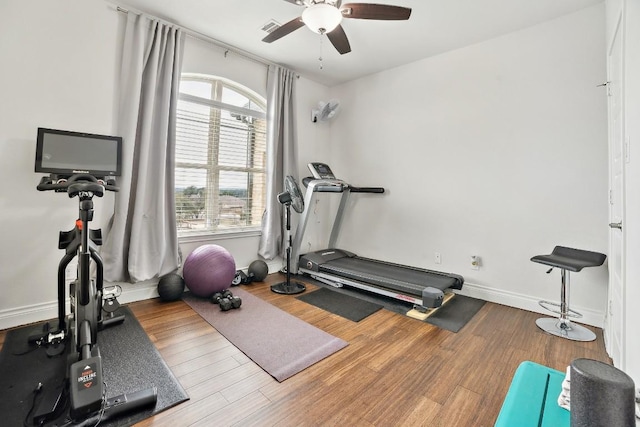 workout room with visible vents, a ceiling fan, baseboards, and wood finished floors