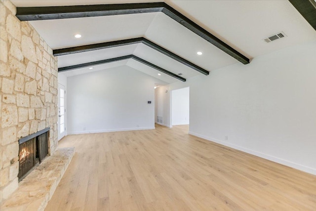 unfurnished living room featuring visible vents, vaulted ceiling with beams, baseboards, a stone fireplace, and wood finished floors