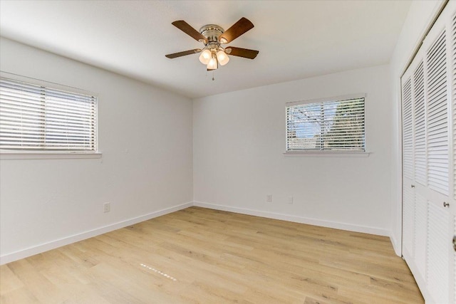 unfurnished bedroom with light wood-style flooring, multiple windows, baseboards, and a closet