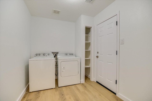 washroom featuring visible vents, baseboards, washer and clothes dryer, laundry area, and light wood-style flooring