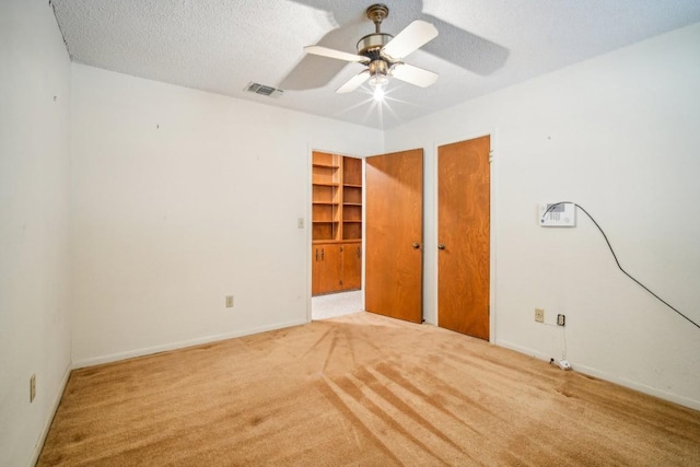 spare room with visible vents, a ceiling fan, a textured ceiling, carpet floors, and baseboards