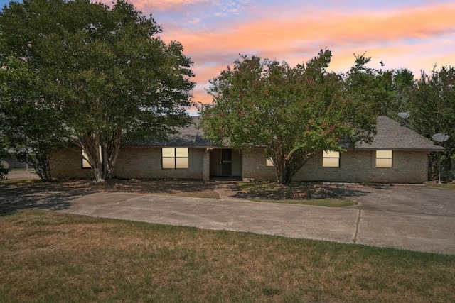 view of front facade featuring a front yard, brick siding, and driveway