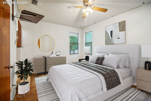 bedroom featuring visible vents, a textured ceiling, and a ceiling fan