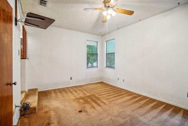 spare room with a ceiling fan, baseboards, visible vents, carpet floors, and a textured ceiling