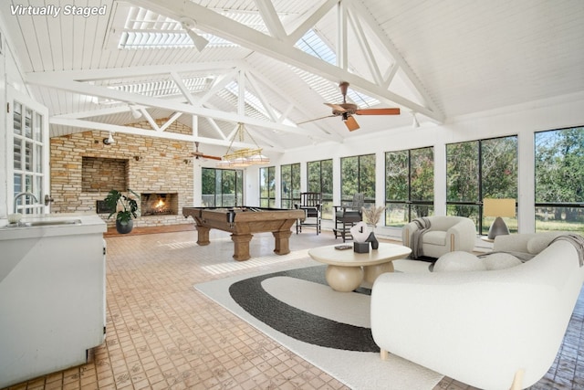 sunroom with a sink, a stone fireplace, pool table, lofted ceiling, and ceiling fan