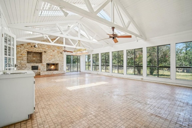 unfurnished sunroom with ceiling fan, vaulted ceiling with skylight, and a sink