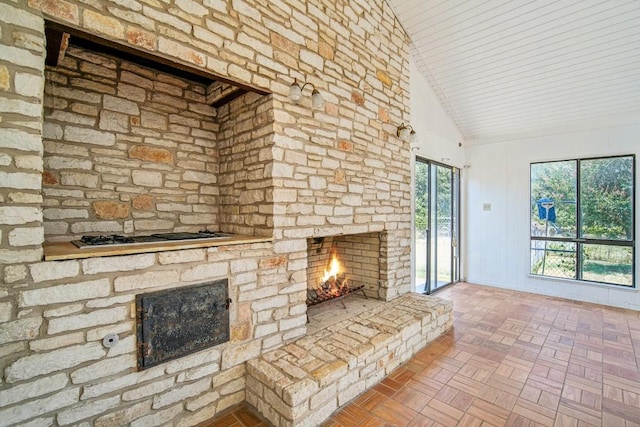 unfurnished living room with high vaulted ceiling and a stone fireplace