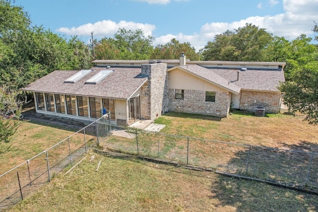 back of property featuring a sunroom, a shingled roof, a chimney, fence private yard, and a lawn