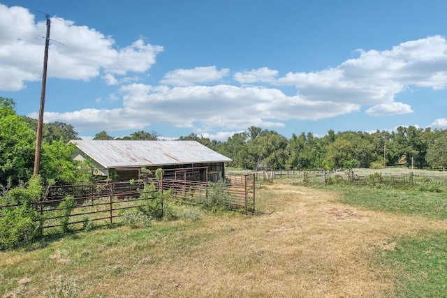 view of yard with an outdoor structure, a rural view, and an exterior structure