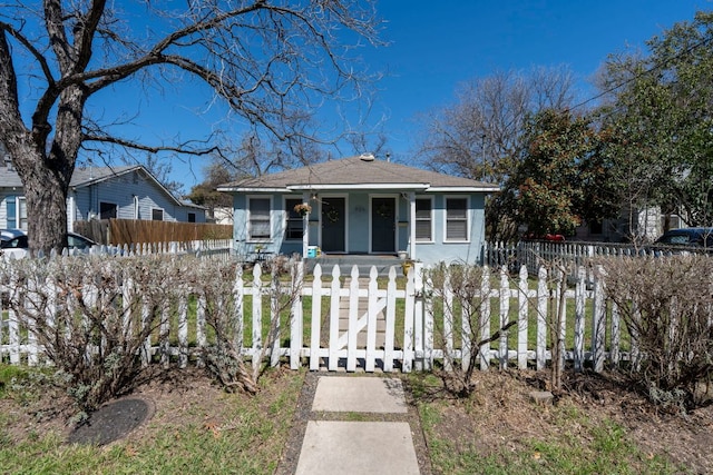 bungalow featuring a fenced front yard, stucco siding, a porch, and roof with shingles