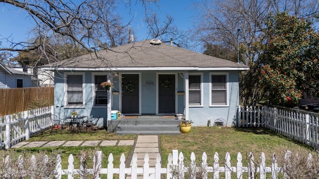 bungalow-style house featuring a porch, a shingled roof, stucco siding, a front lawn, and fence private yard