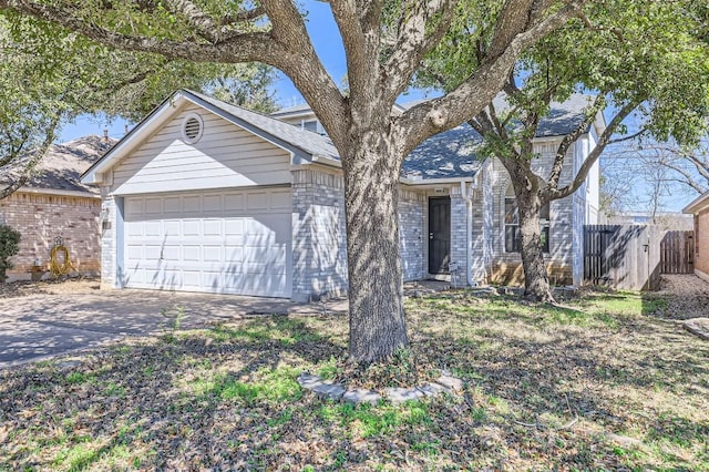 view of front of property featuring an attached garage, fence, brick siding, and driveway