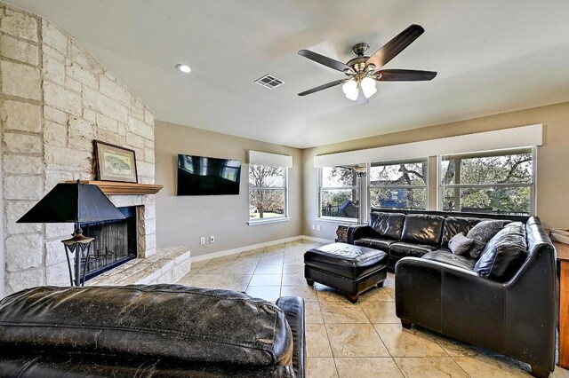 tiled living area with visible vents, baseboards, a stone fireplace, and a ceiling fan