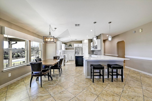 dining room featuring vaulted ceiling, baseboards, visible vents, and arched walkways