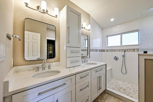 bathroom featuring double vanity, walk in shower, and a sink