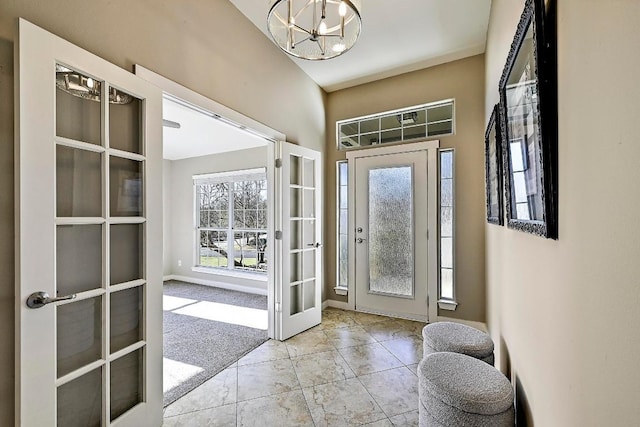 foyer featuring a notable chandelier, carpet flooring, french doors, and baseboards