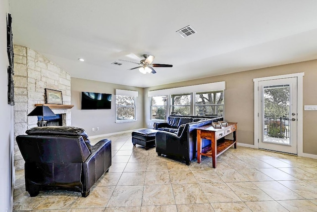 living room with visible vents, a stone fireplace, light tile patterned floors, baseboards, and ceiling fan