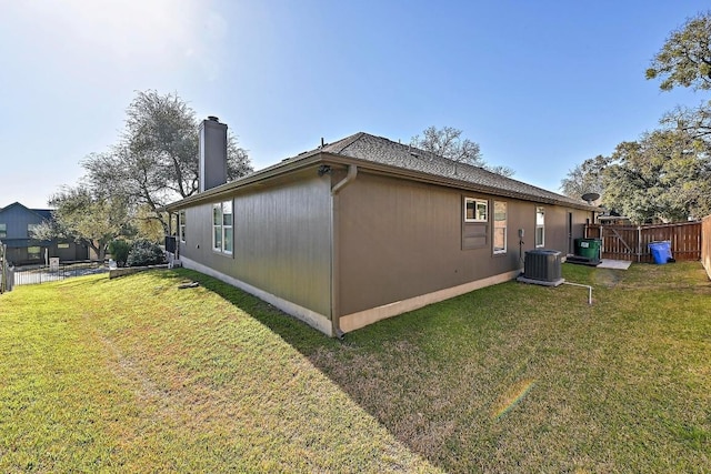 view of home's exterior with a lawn, central AC, a chimney, and fence