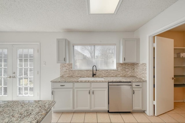 kitchen with tasteful backsplash, dishwasher, french doors, and a sink