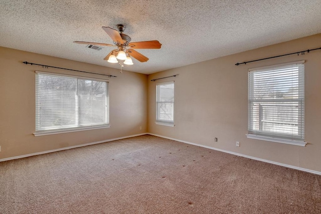 carpeted empty room featuring visible vents, a textured ceiling, baseboards, and a ceiling fan