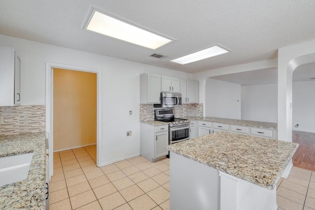 kitchen with backsplash, light tile patterned flooring, visible vents, and appliances with stainless steel finishes