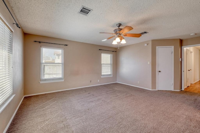 spare room featuring visible vents, carpet floors, baseboards, and ceiling fan