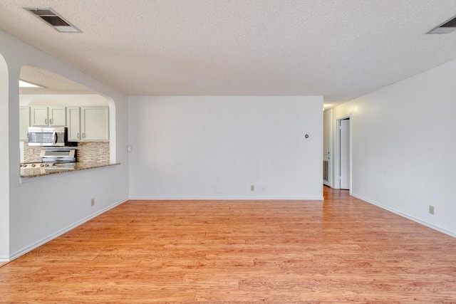 unfurnished living room with visible vents, light wood finished floors, and a textured ceiling