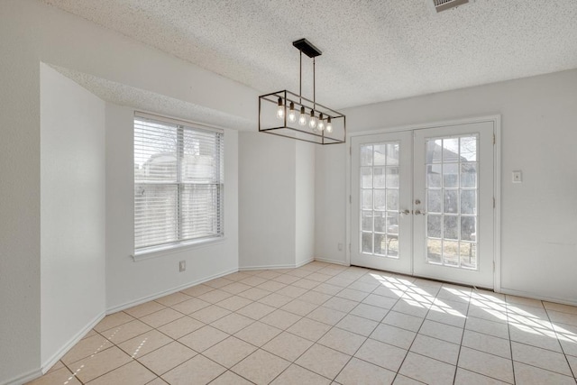 unfurnished dining area with french doors, a textured ceiling, a healthy amount of sunlight, and light tile patterned flooring