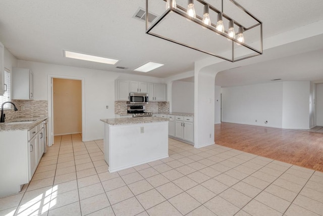 kitchen with visible vents, open floor plan, light tile patterned floors, appliances with stainless steel finishes, and a sink