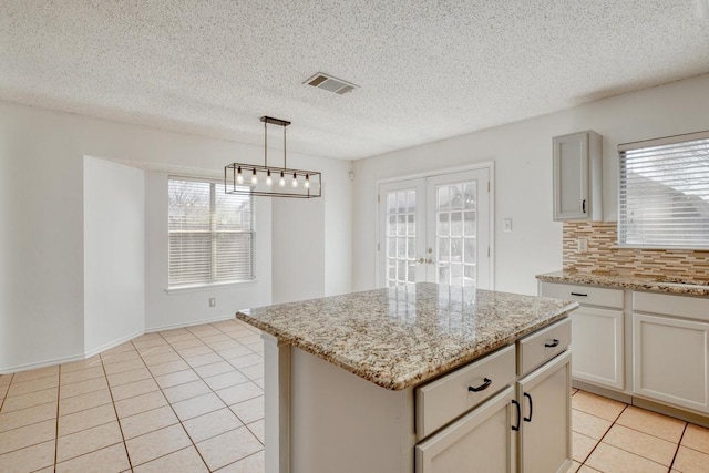 kitchen featuring light tile patterned flooring, visible vents, french doors, and decorative backsplash