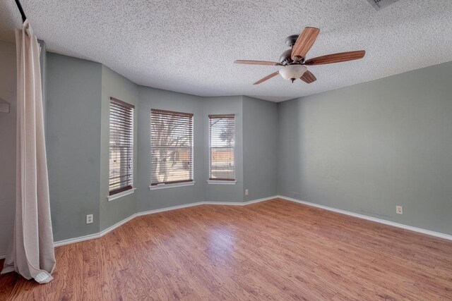 spare room with ceiling fan, a textured ceiling, baseboards, and wood finished floors