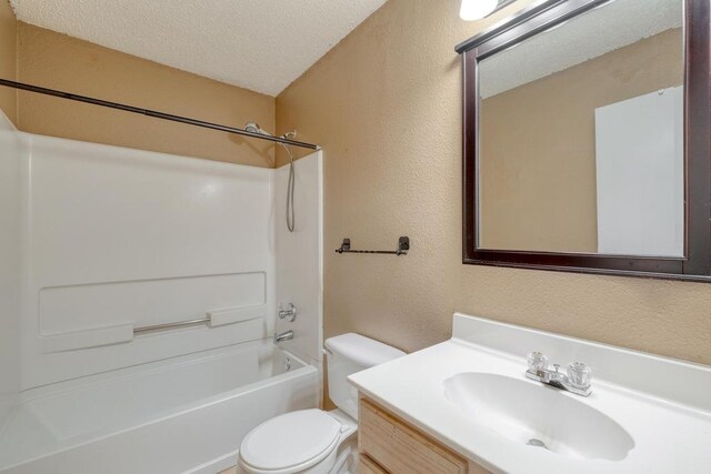 bathroom with vanity, tub / shower combination, a textured ceiling, toilet, and a textured wall