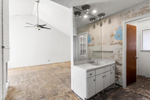 bathroom featuring lofted ceiling, a textured ceiling, vanity, and a ceiling fan