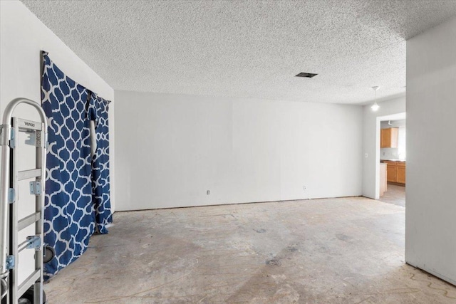 empty room with visible vents, concrete floors, and a textured ceiling