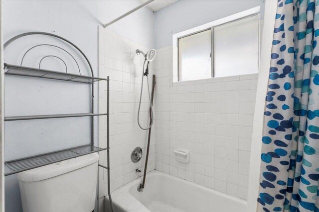 bathroom featuring toilet and shower / bath combo with shower curtain