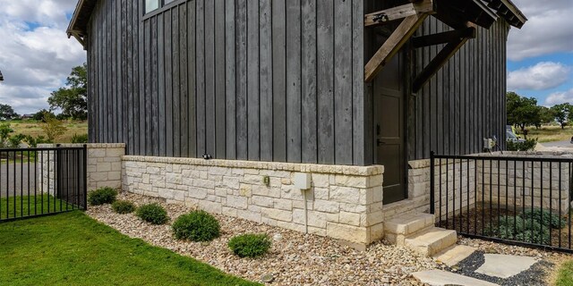 view of side of property featuring stone siding, board and batten siding, and fence